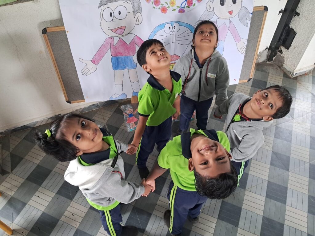 A group of children holding hands and looking into the camera from the top angle